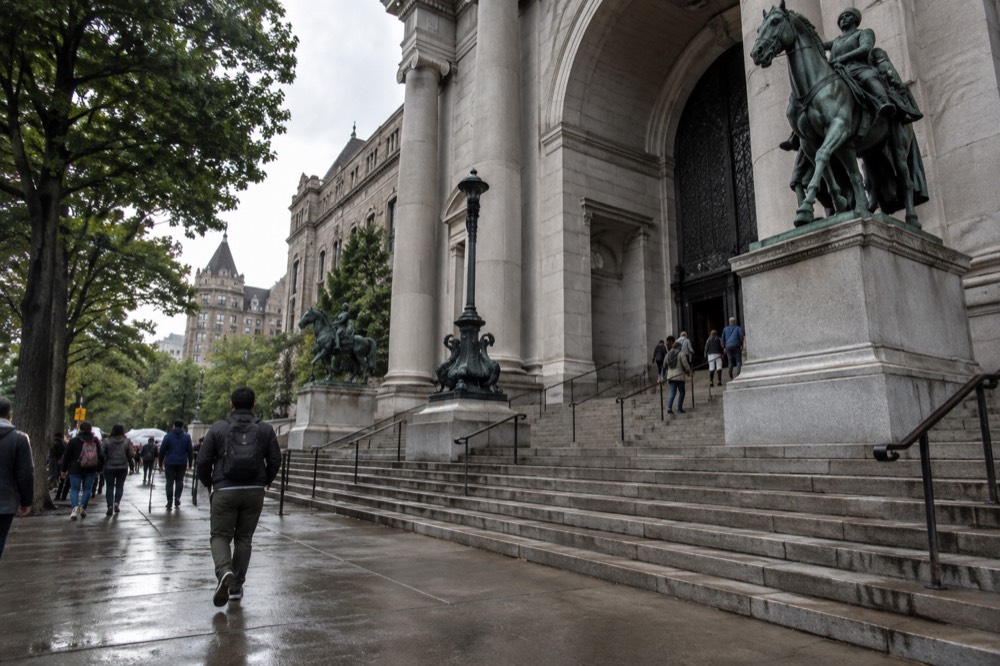 The stone facade and entrance steps of the American Museum of Natural History on a busy morning