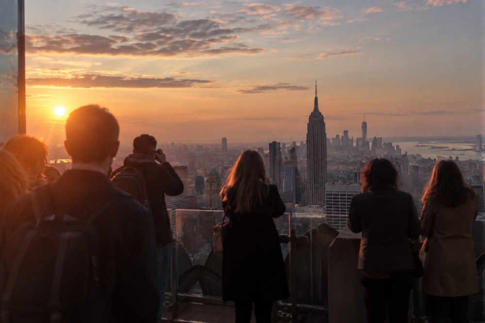 Visitors looking out over the Manhattan skyline from an open-air observation deck at dusk