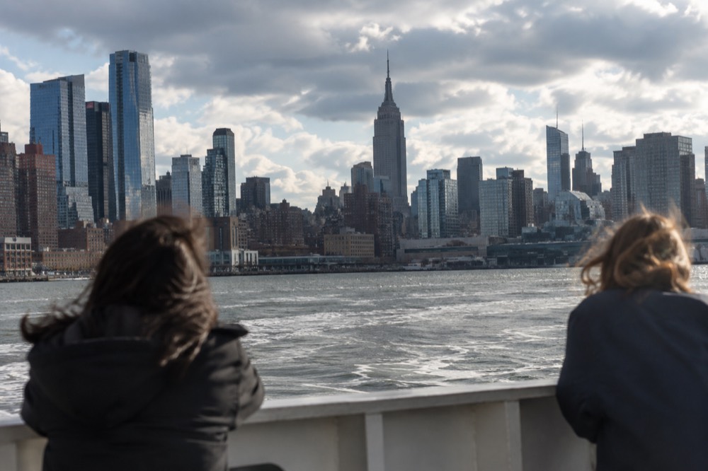 A view across the Manhattan skyline from a harbor boat, with the Empire State Building rising above Midtown towers.