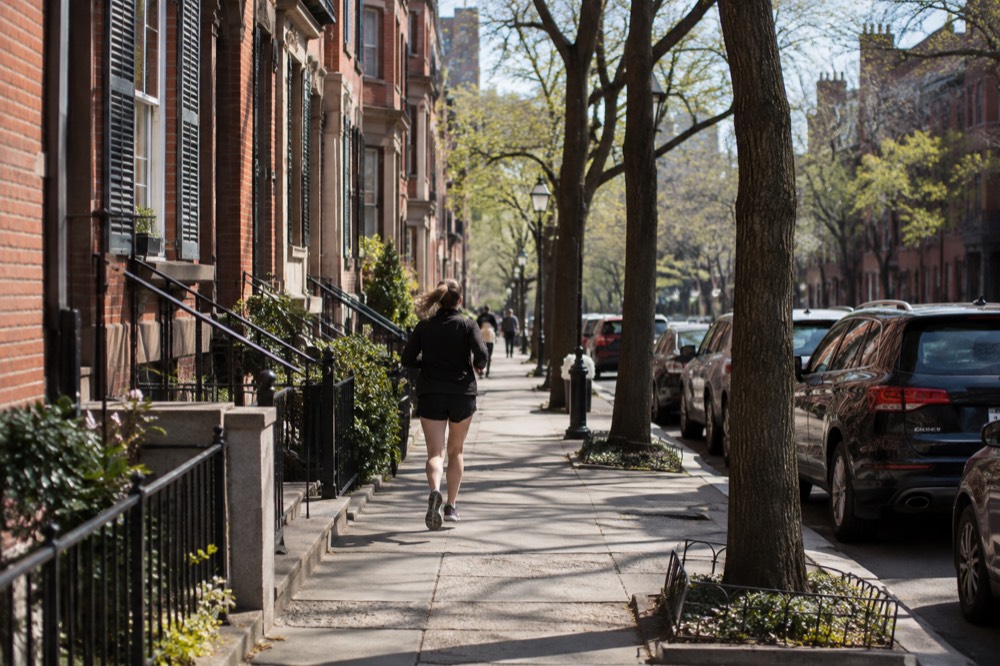 Rowhouses on a narrow Boston street with brick facades lit by morning sun