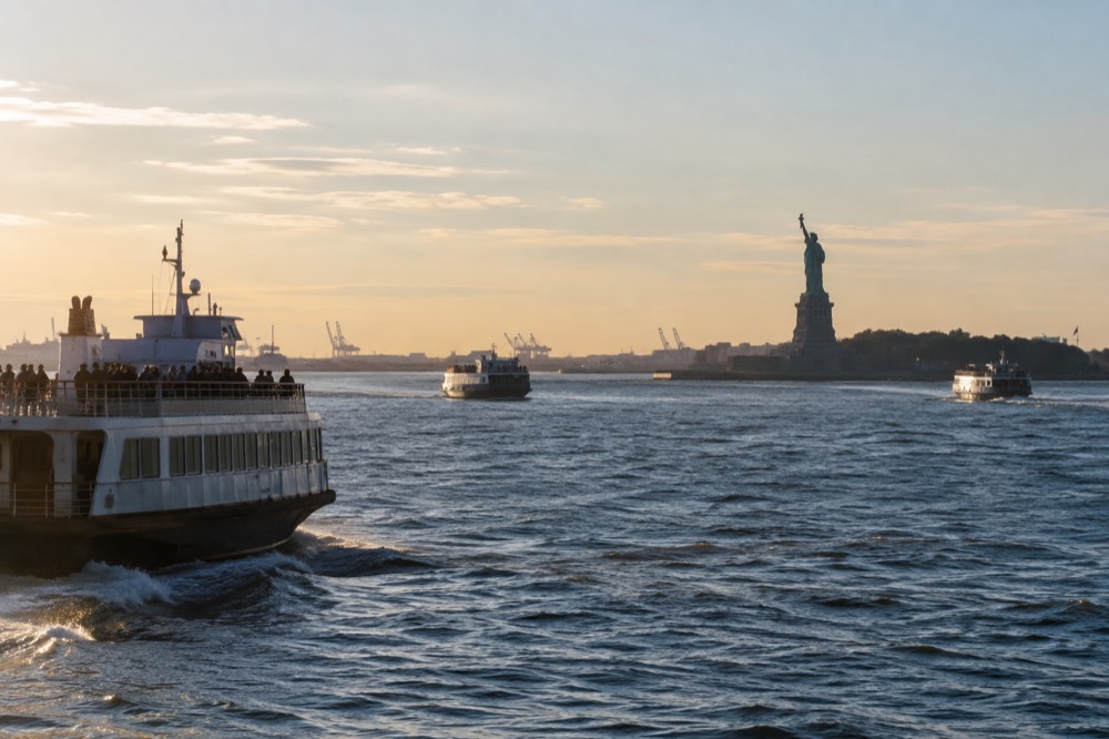The New York Harbor seen from the water, with the Statue of Liberty in the distance and boat traffic on the waves.