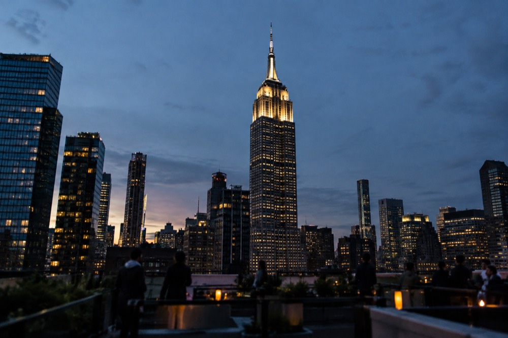 The Empire State Building at dusk from a Midtown rooftop, with the tower lit against a deep blue sky