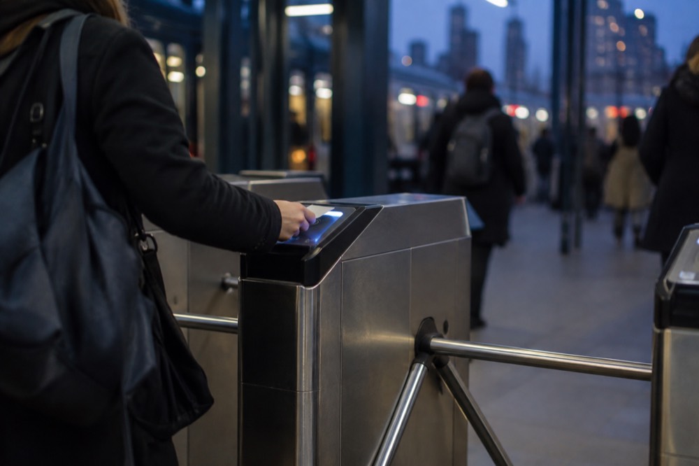 A subway turnstile with a rider tapping a contactless card
