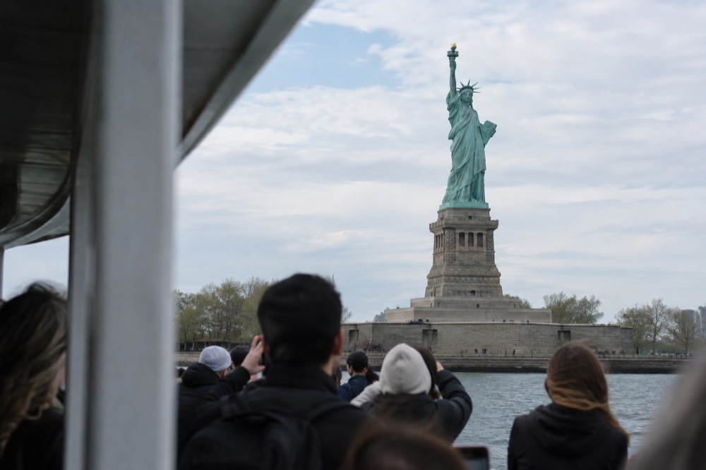 Ferry passengers looking up at the Statue of Liberty from the deck on a clear day
