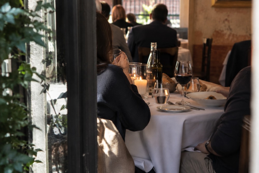 A candlelit Italian restaurant table in a downtown Manhattan dining room with wine glasses and bread