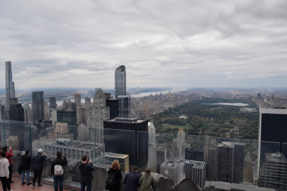 The observation deck at Top of the Rock with visitors looking out over Central Park and the Manhattan skyline
