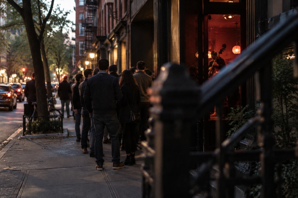 Evening crowd outside a Village jazz club with a lit marquee