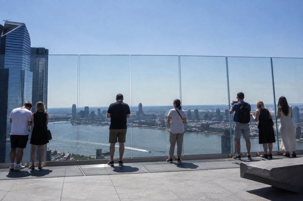 Observation deck visitors looking out over the Hudson River toward New Jersey at sunset