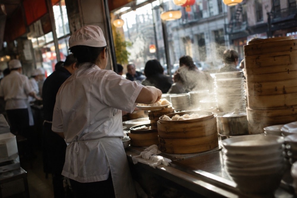 Dumplings being served at a busy counter in a Chinatown restaurant near SoHo