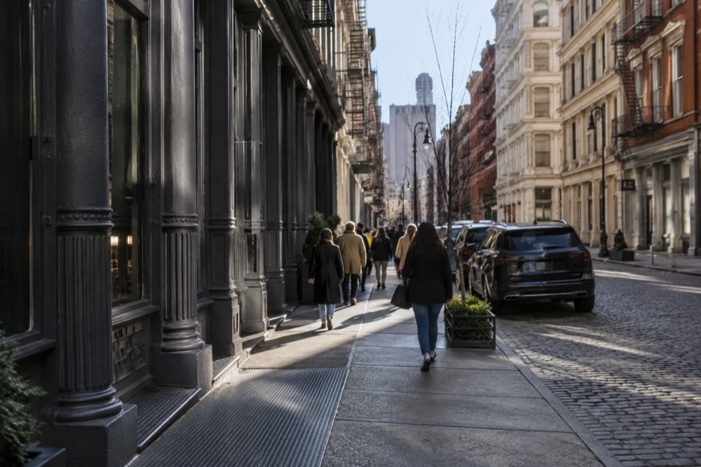 A narrow SoHo street lined with cast-iron facades and shoppers in the morning
