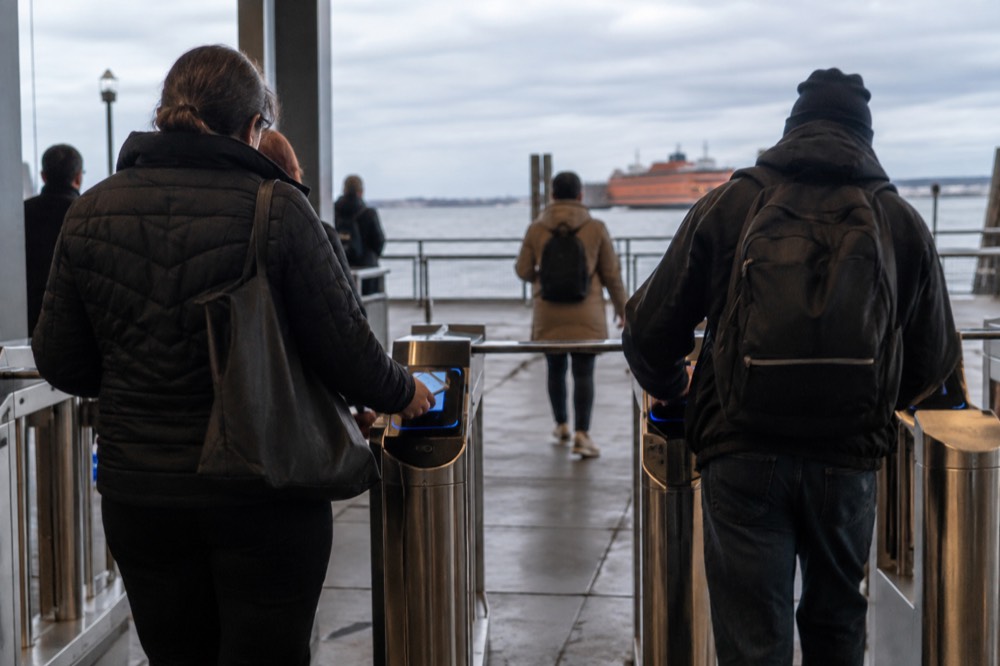 Passengers tapping a phone at an OMNY reader at a ferry terminal gate