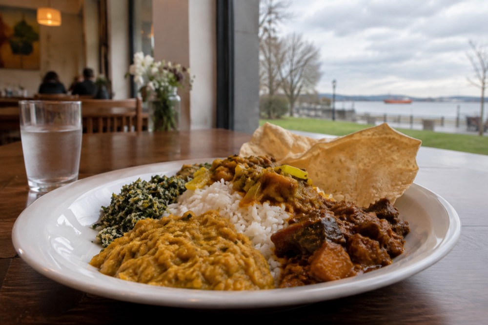 A plate of Sri Lankan rice and curry dishes served on a table in a small restaurant