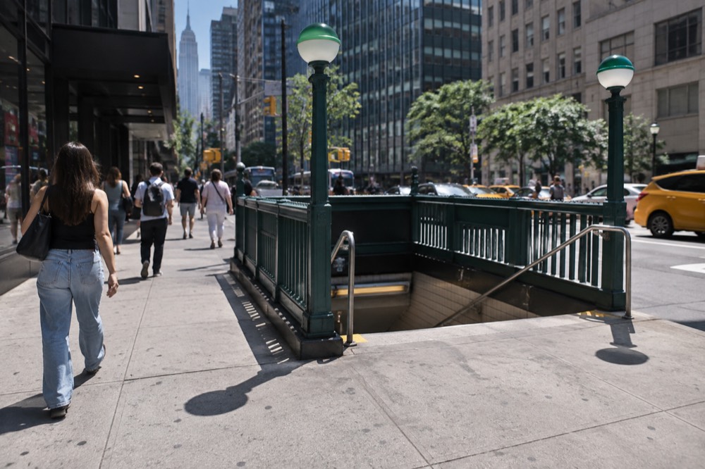 A subway entrance on a Manhattan street corner with pedestrians passing