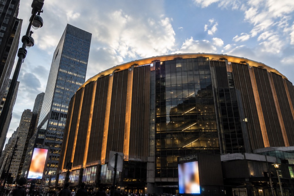 The illuminated Madison Square Garden marquee at dusk above the Penn Station entrance