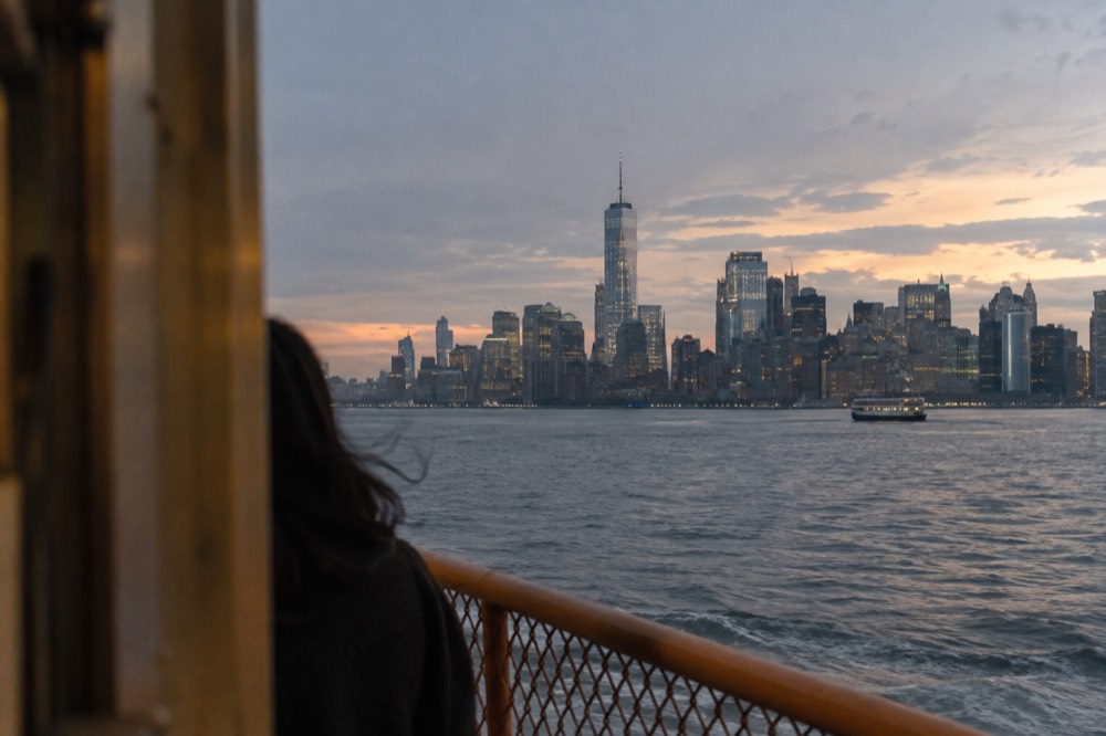 The Lower Manhattan skyline and harbor at dusk seen across the water