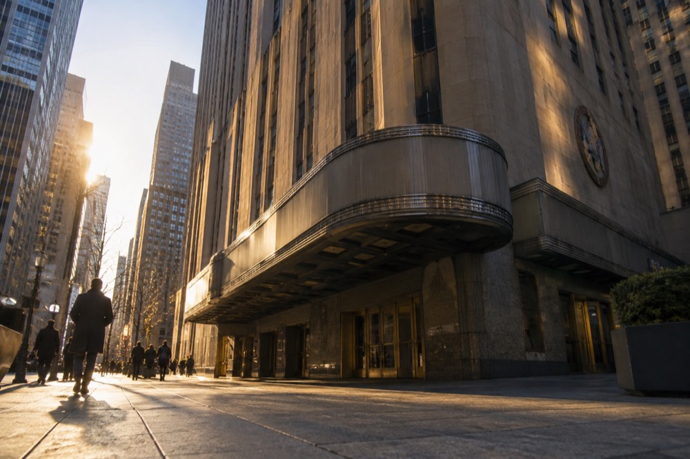 The exterior marquee of Radio City Music Hall glowing above 6th Avenue at dusk