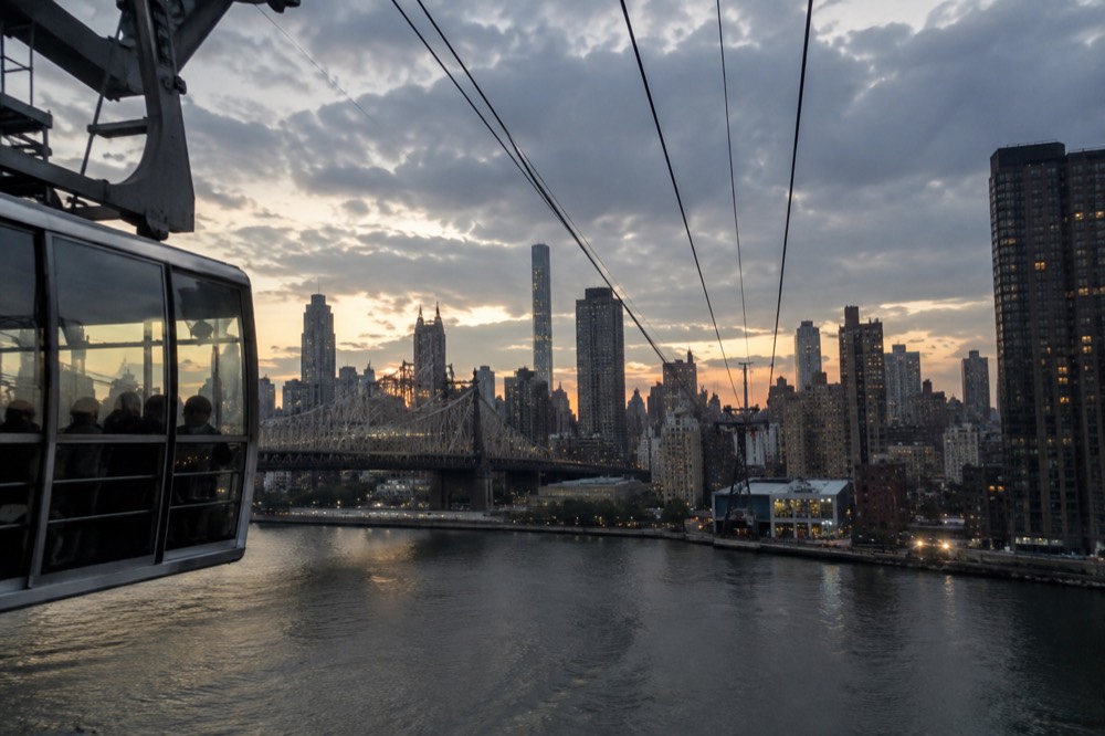 The Roosevelt Island Tram cables stretching across the East River toward the Manhattan station at dusk