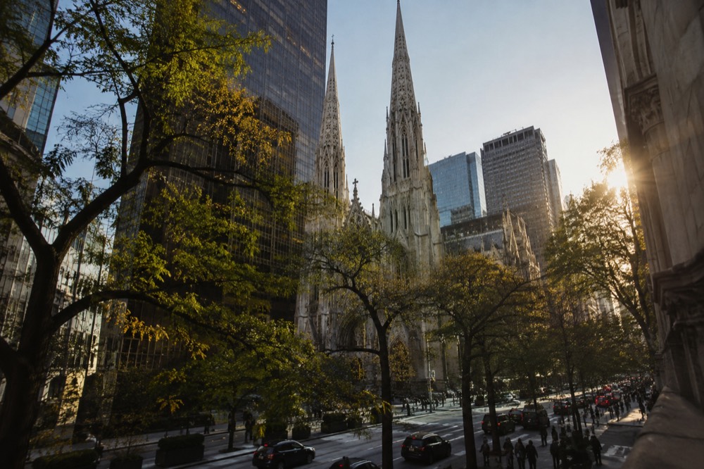 The cathedral spires rising behind trees along Fifth Avenue on a clear afternoon