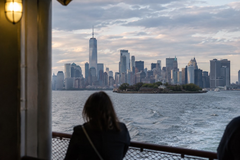 A ferry boat crossing the harbor with the Manhattan skyline and harbor islands in view
