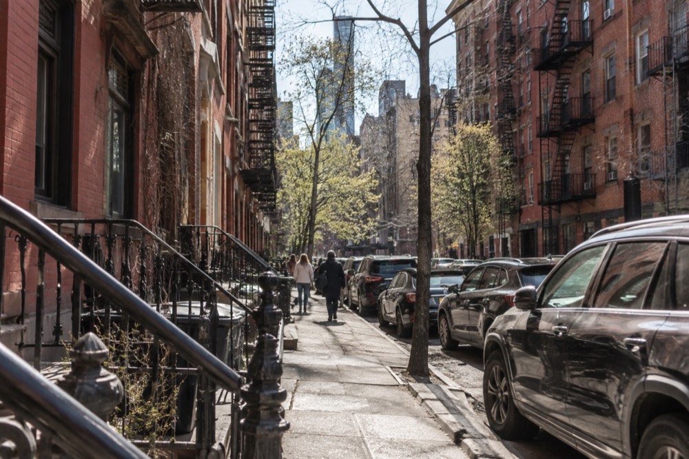 A historic brick tenement building on a narrow Lower East Side street with fire escapes