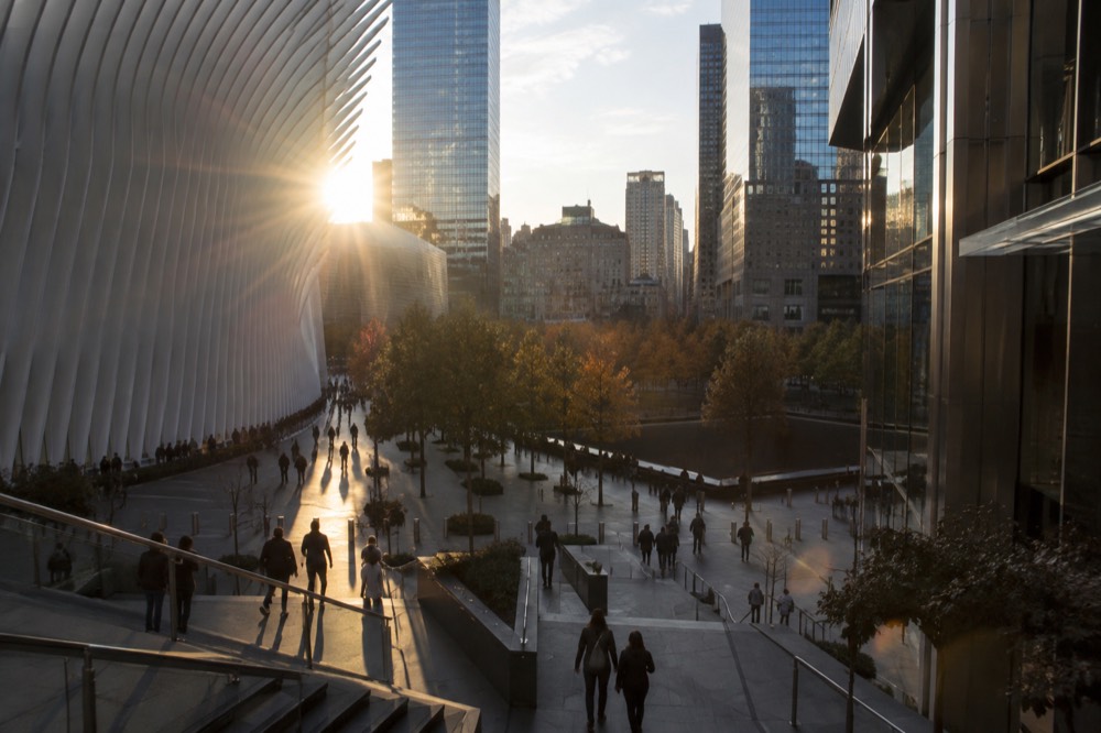 Visitors walking between The Oculus and the 9/11 Memorial pools at the World Trade Center
