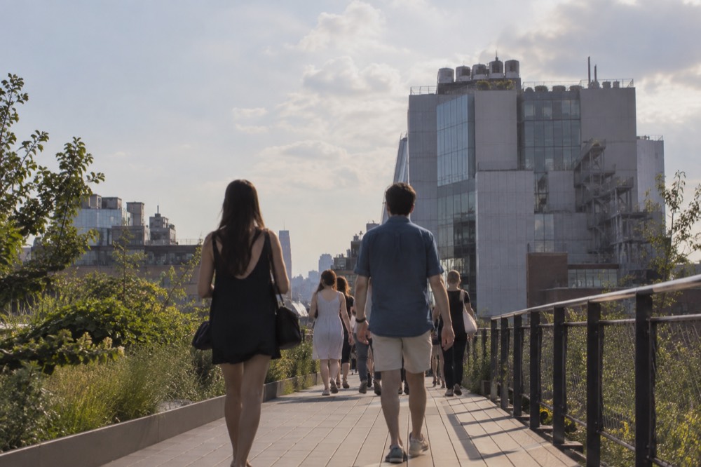 Pedestrians walking the High Line toward the Whitney Museum building on a sunny afternoon