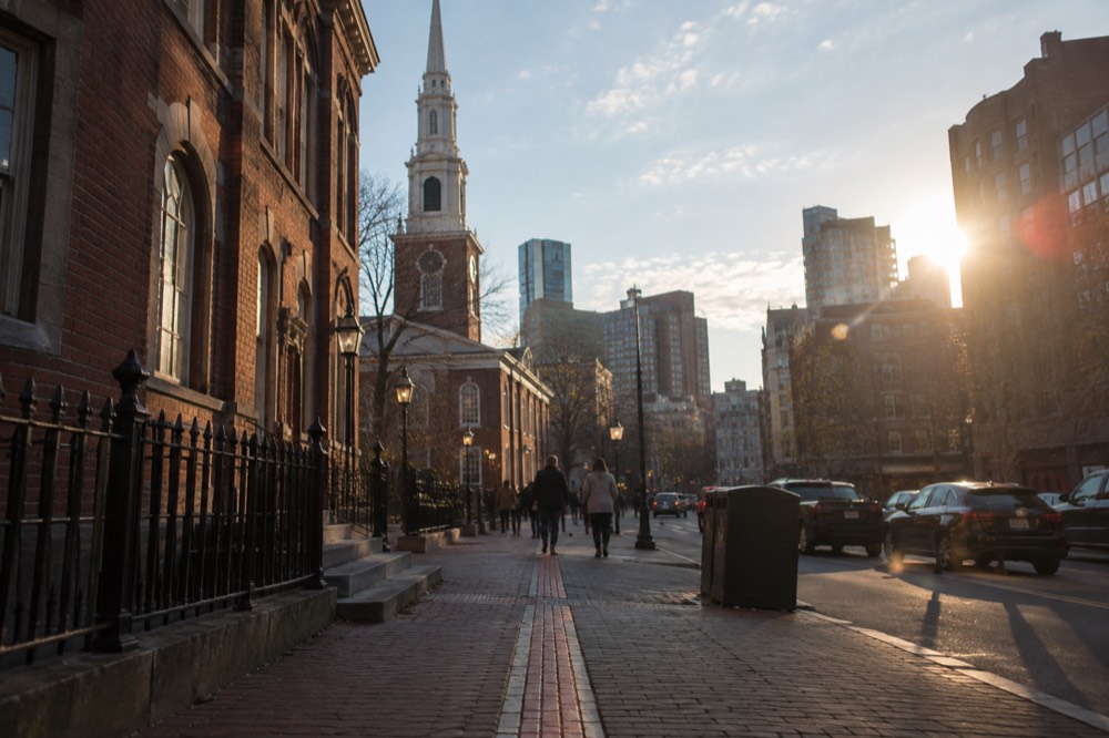 The red brick Freedom Trail line running along a sidewalk past historic buildings