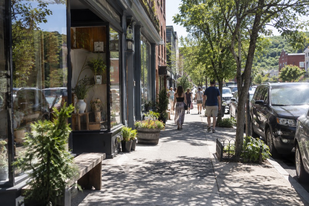 A village street of small shops with pedestrians browsing on a bright day