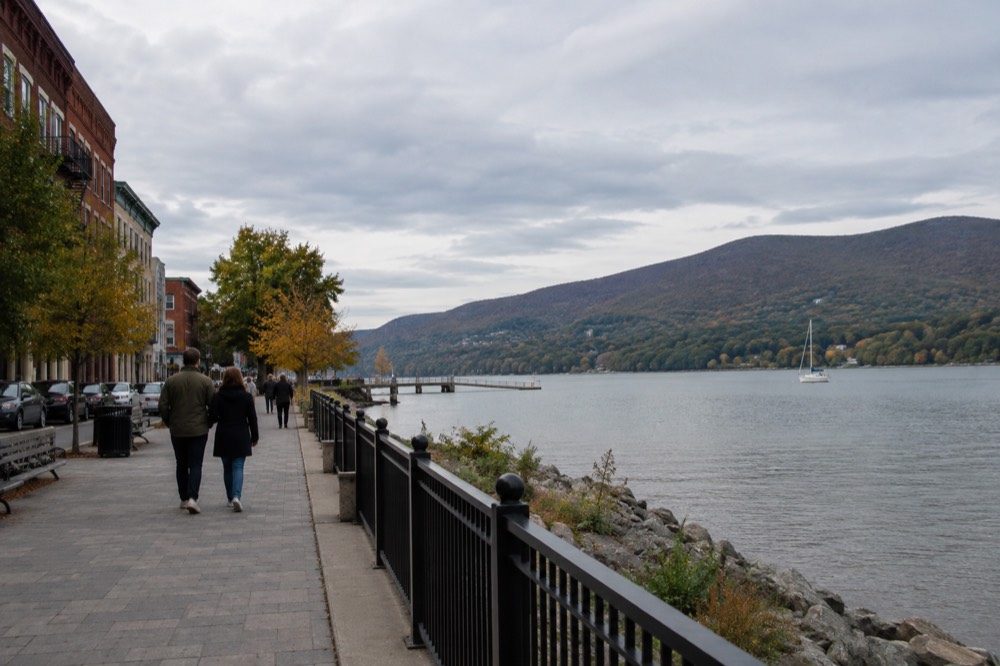 A small riverside town with a main street of brick storefronts and hills behind