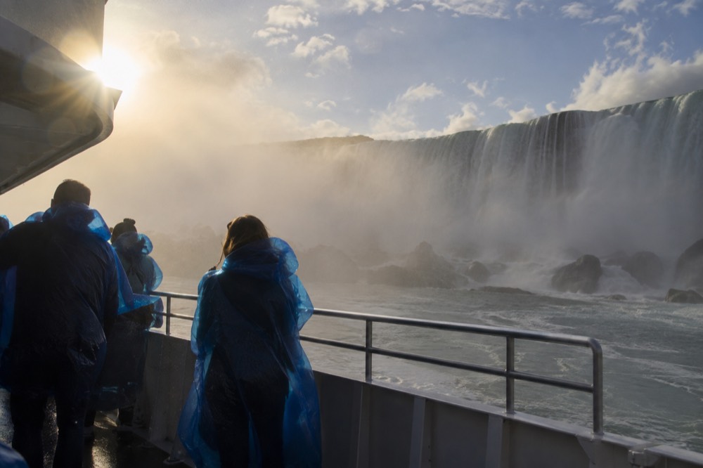 Travelers wearing rain ponchos on a boat deck with mist rolling over the railing