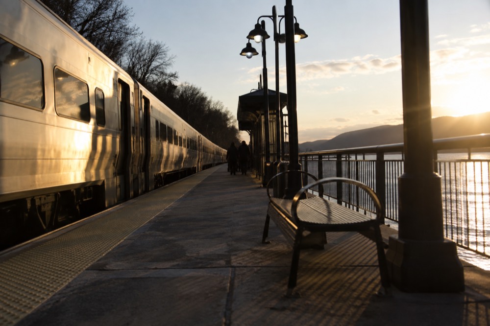 Commuter train pulling away from a Hudson Line platform beside the river