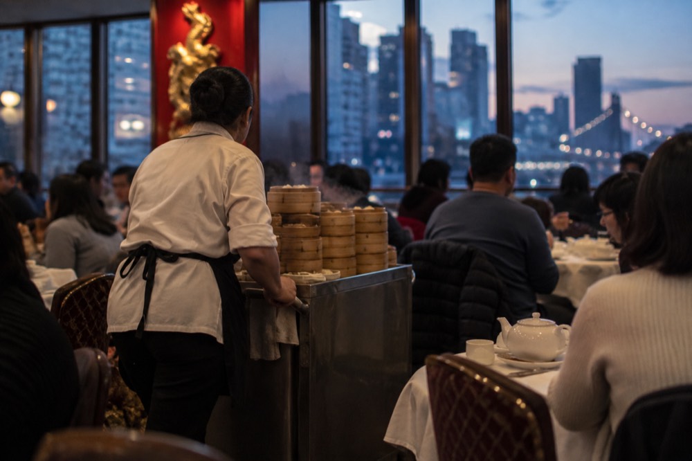 A dim sum cart moving between tables in a busy Chinatown restaurant