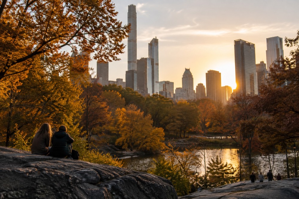 Central Park in autumn with the Manhattan skyline rising behind golden trees