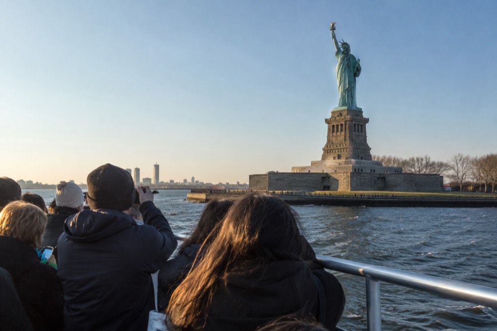 A sightseeing boat passing close to the Statue of Liberty in New York Harbor