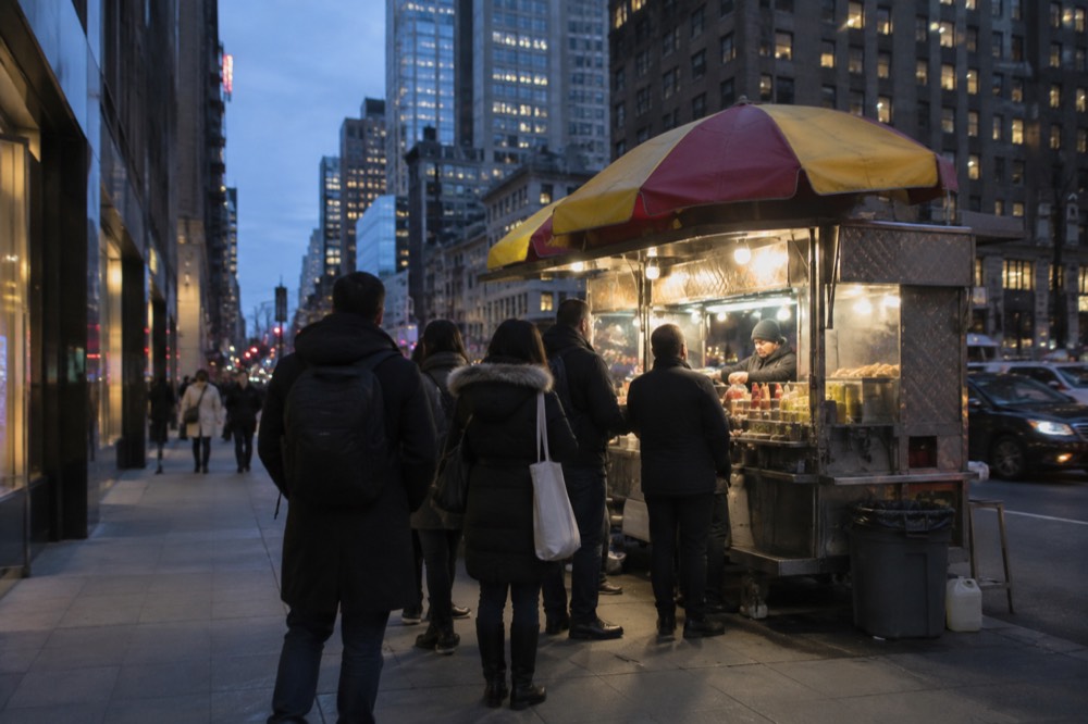 A halal food cart serving lunch to a queue on a Midtown sidewalk