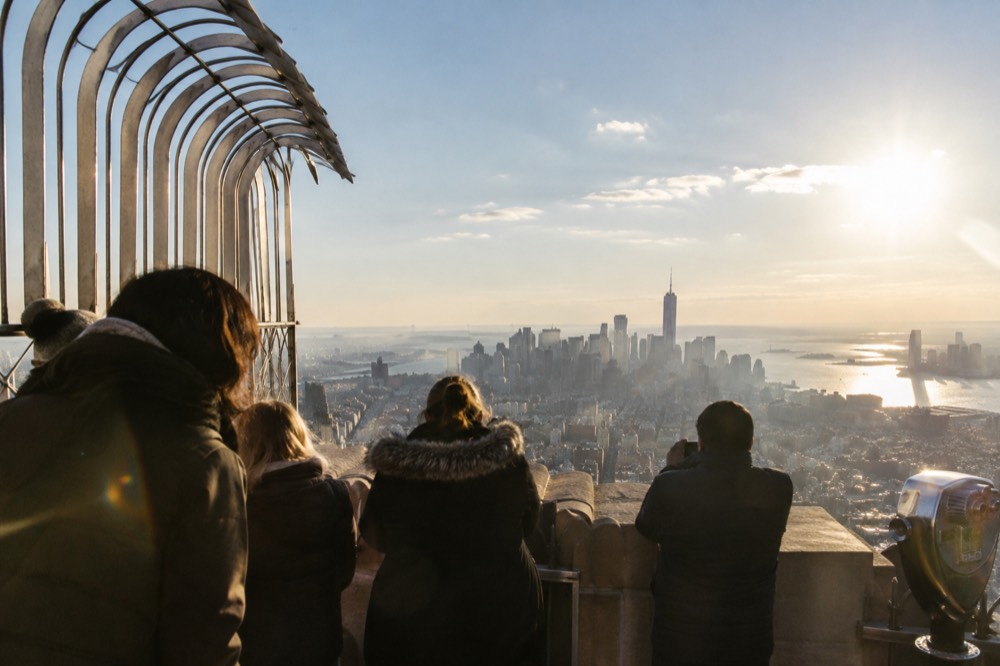 Visitors on the open-air 86th floor observation deck of the Empire State Building looking over Manhattan