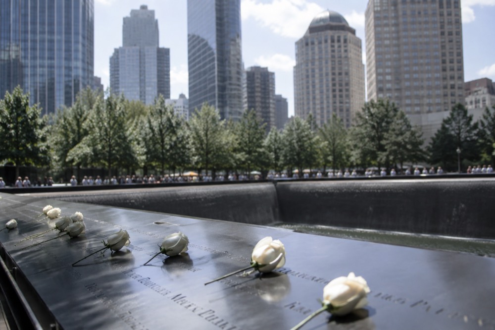 White roses resting on the engraved names around a memorial pool