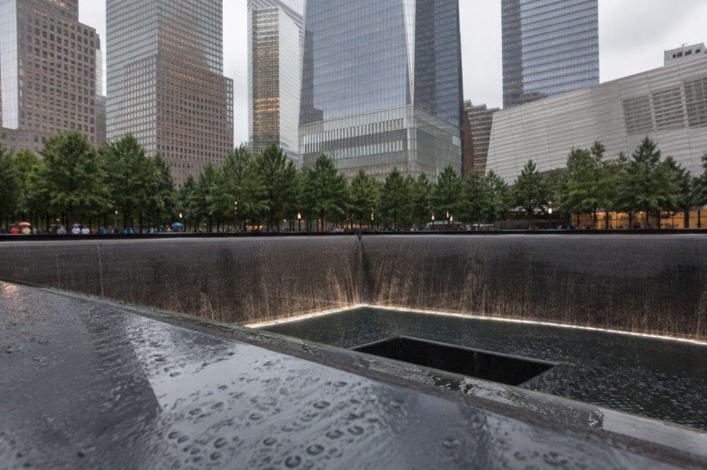 Two large reflecting pools set into a stone plaza between tall towers