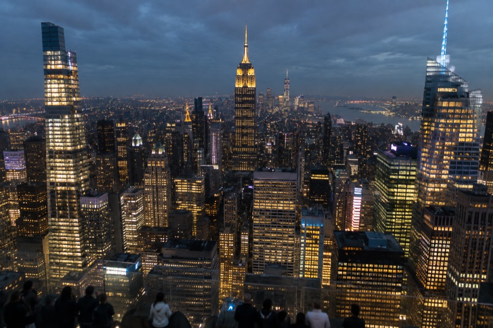 A city skyline at night with illuminated towers seen from a high observation deck