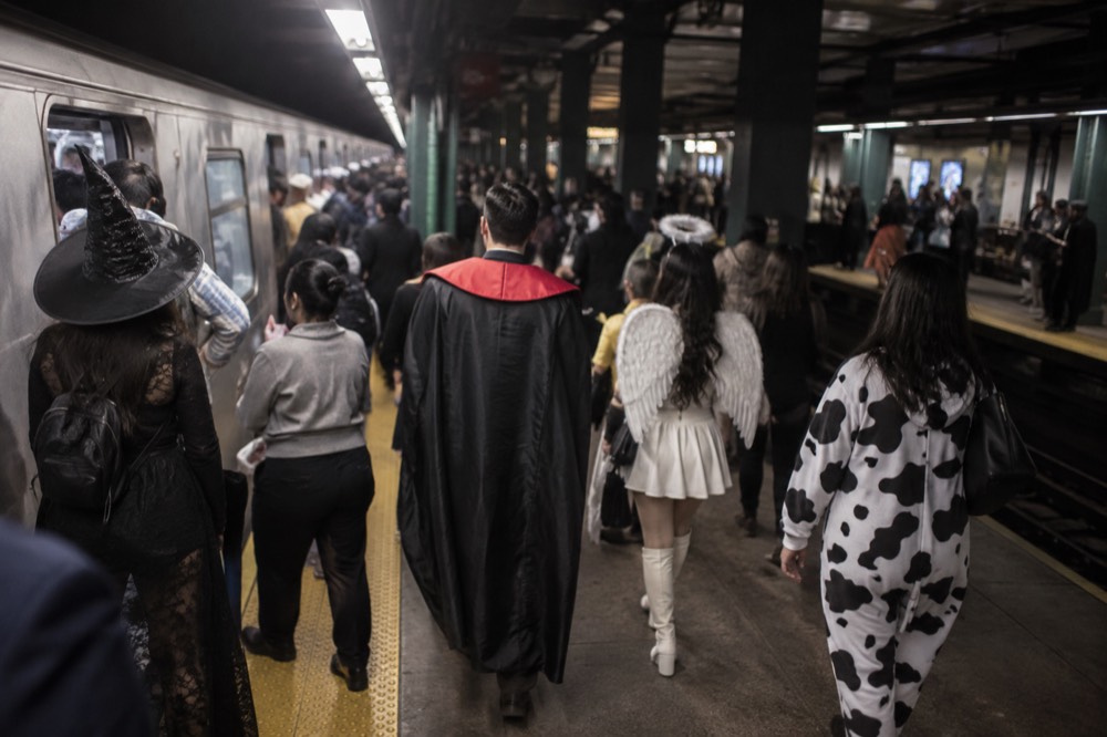 A busy subway platform at night filled with passengers in costume