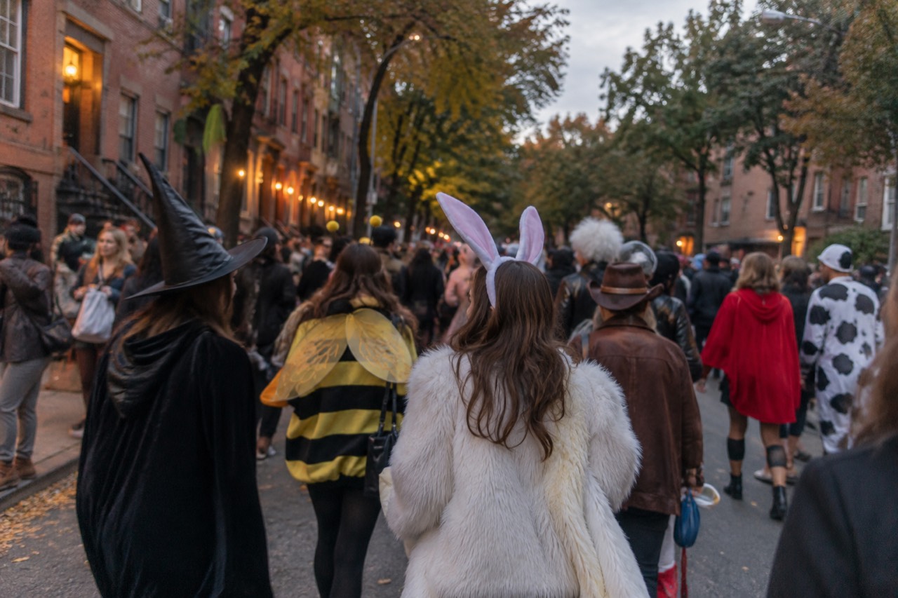 Costumed crowds filling a Greenwich Village street on a fall evening