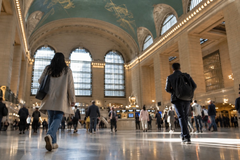 A grand terminal concourse with a starry painted ceiling and sunlight through tall windows