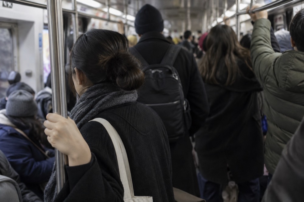 A crowded New York subway car with riders holding the poles