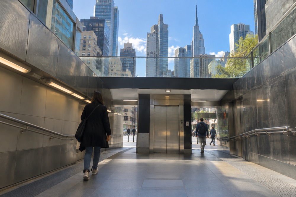 A wide accessible subway station corridor with an elevator in the background