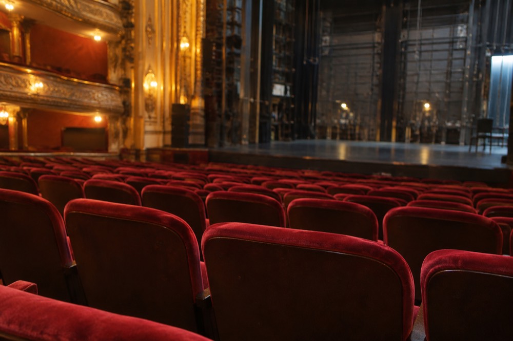 An empty Broadway theater auditorium with red velvet seats before a performance