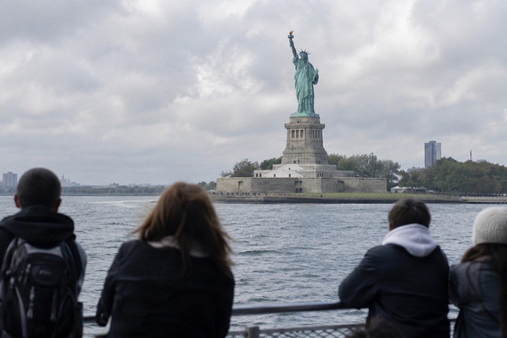 The Statue of Liberty seen from a ferry deck with visitors at the rail