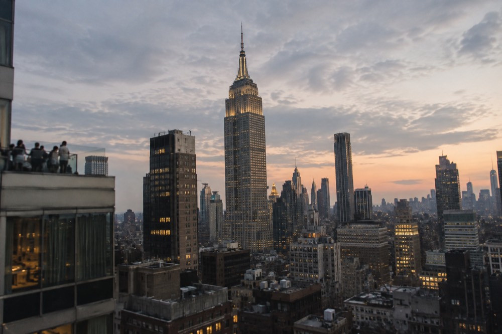 The Empire State Building lit at dusk above Midtown rooftops