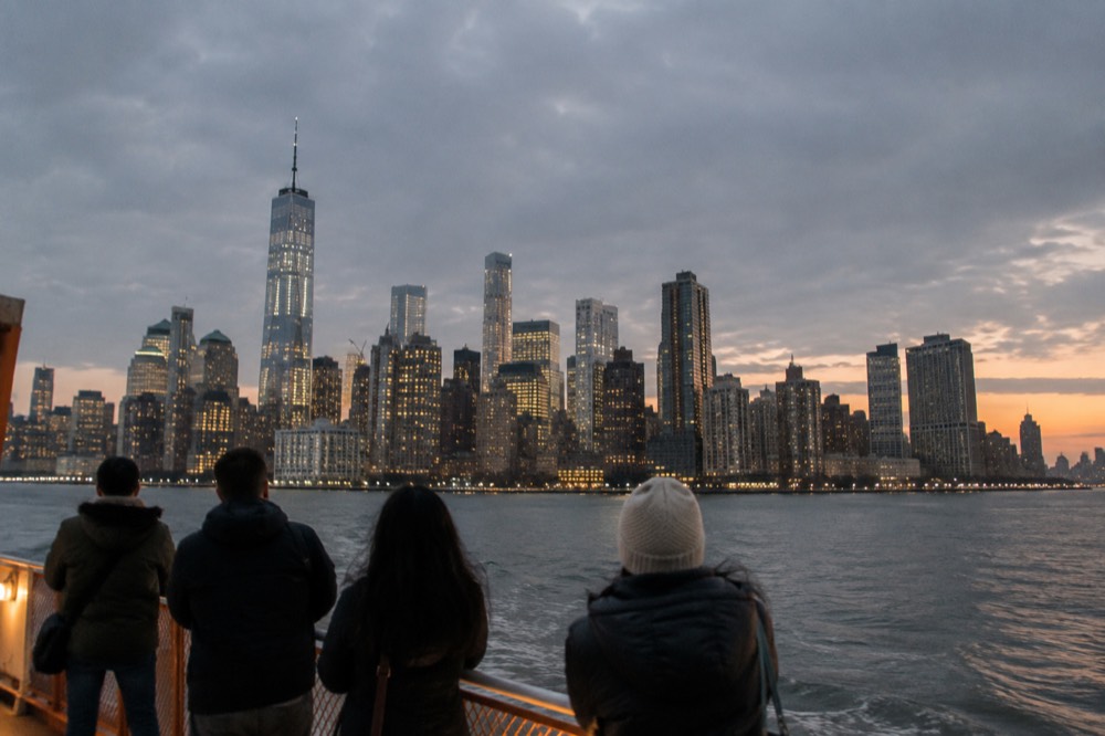 The Lower Manhattan skyline seen across the water from a ferry deck at dusk
