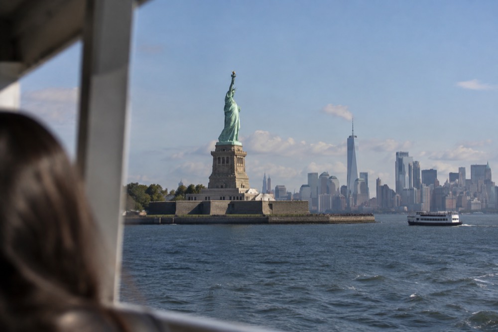 The Statue of Liberty seen from the water with the harbor and skyline behind
