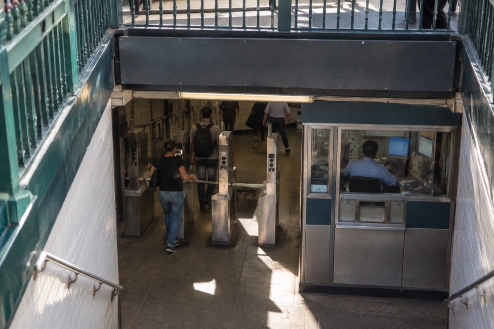 A station booth and turnstiles inside a New York subway entrance